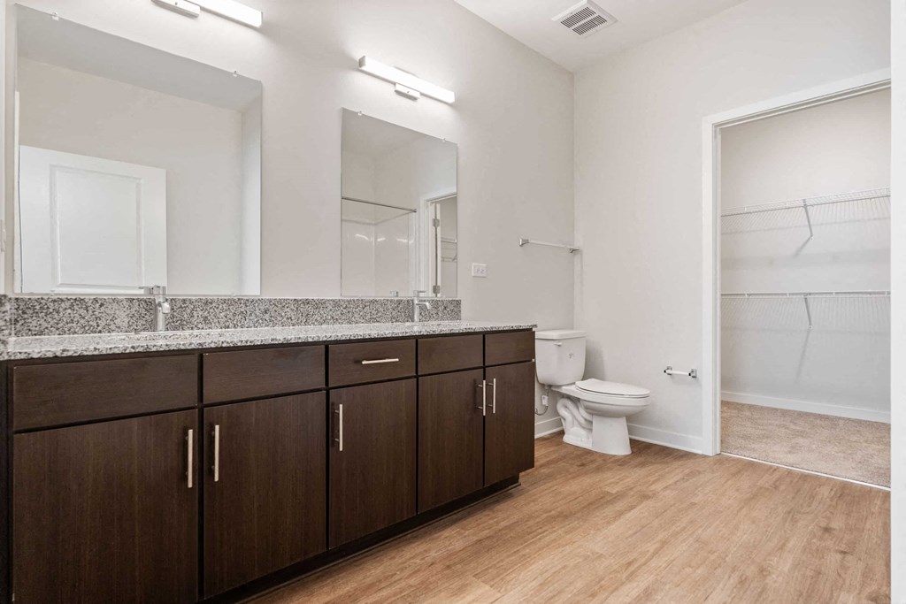 a bathroom with wooden flooring and a mirror and a toilet