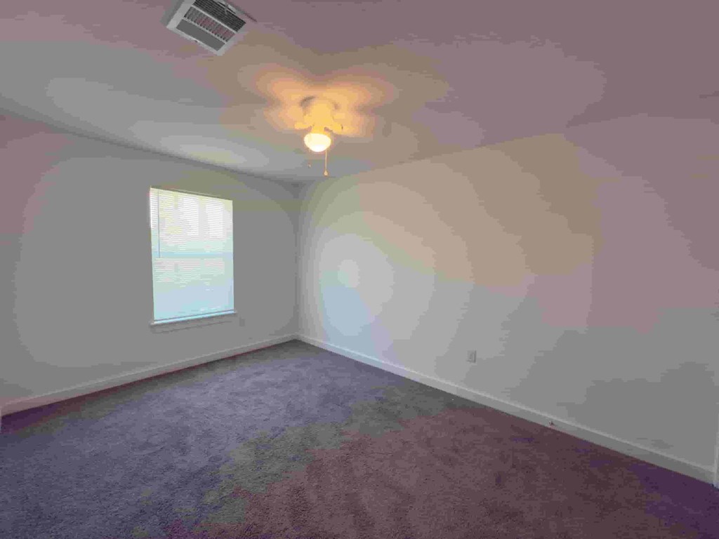 an empty room with pink walls and a ceiling fan
