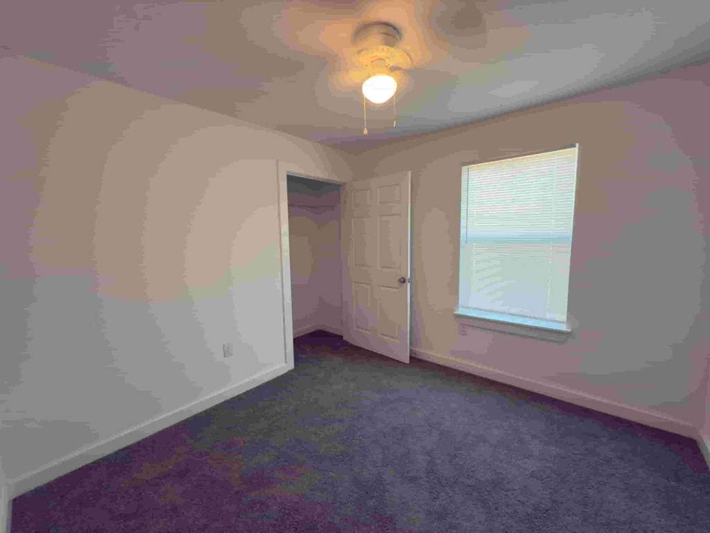 an empty room with a door and a ceiling fan