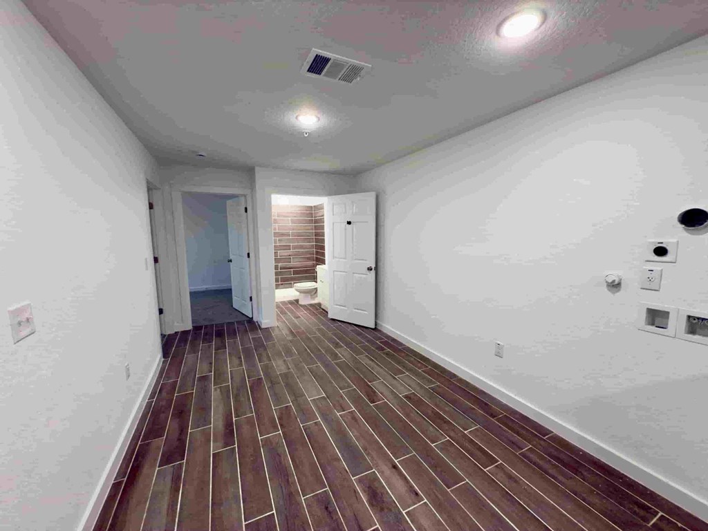 a long hallway with white walls and wood flooring