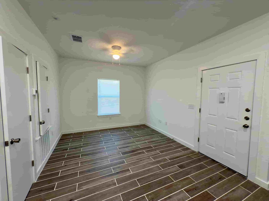 an empty room with a white door and a ceiling fan