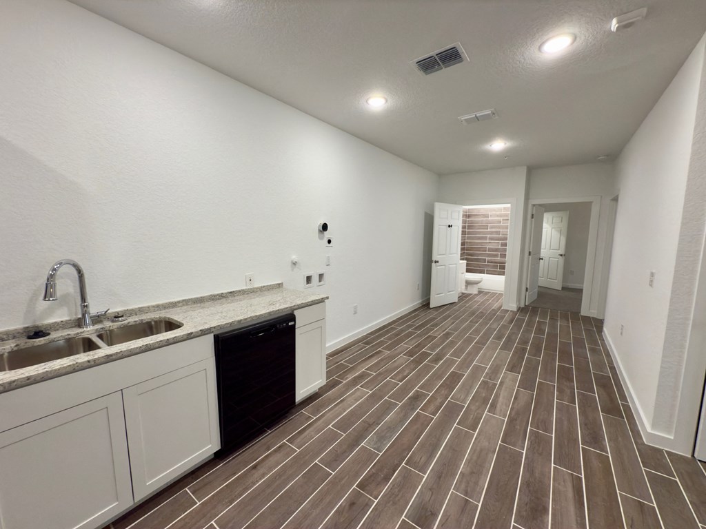 the kitchen and living room of a new home with white walls and tile flooring