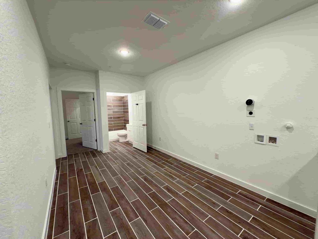 a spacious living room with white walls and wood flooring