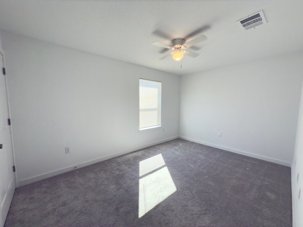 an empty room with a ceiling fan and a window