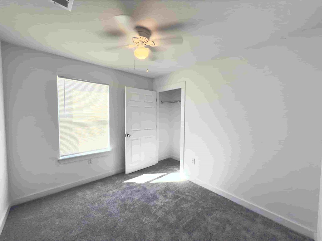 a bedroom with white walls and a ceiling fan