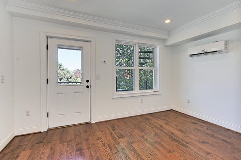 A room with a white door and a window with a view of trees.