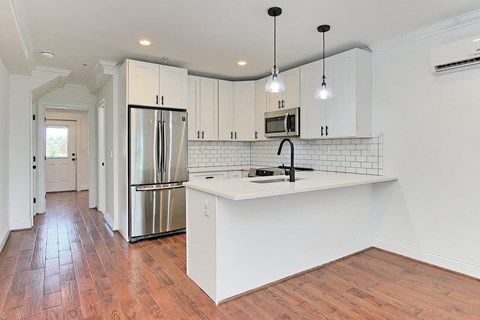 A kitchen with white cabinets and a wooden floor.