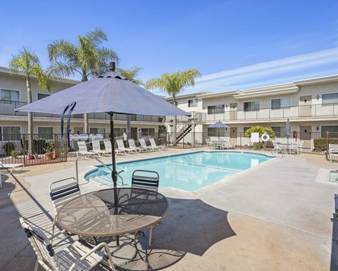 A pool area with a table and chairs and a pool.