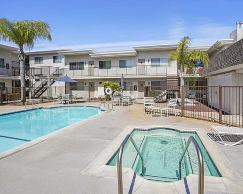 A swimming pool in front of a building with a fence around it.