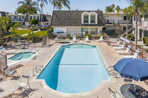 A large swimming pool surrounded by a fence and chairs.