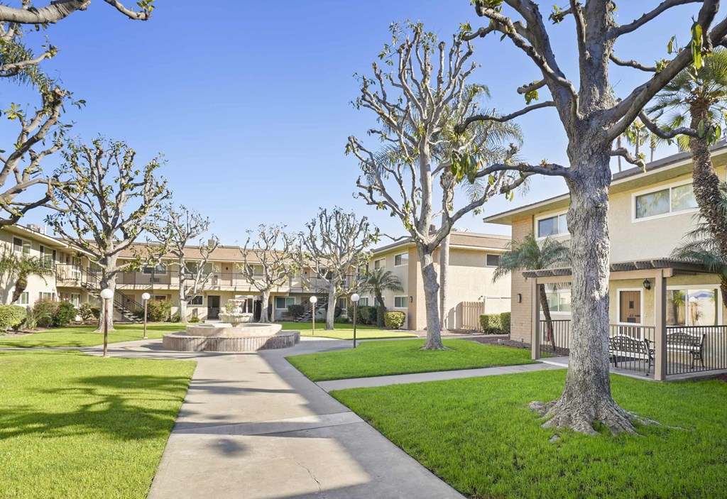 A tree-lined walkway leads to a building.