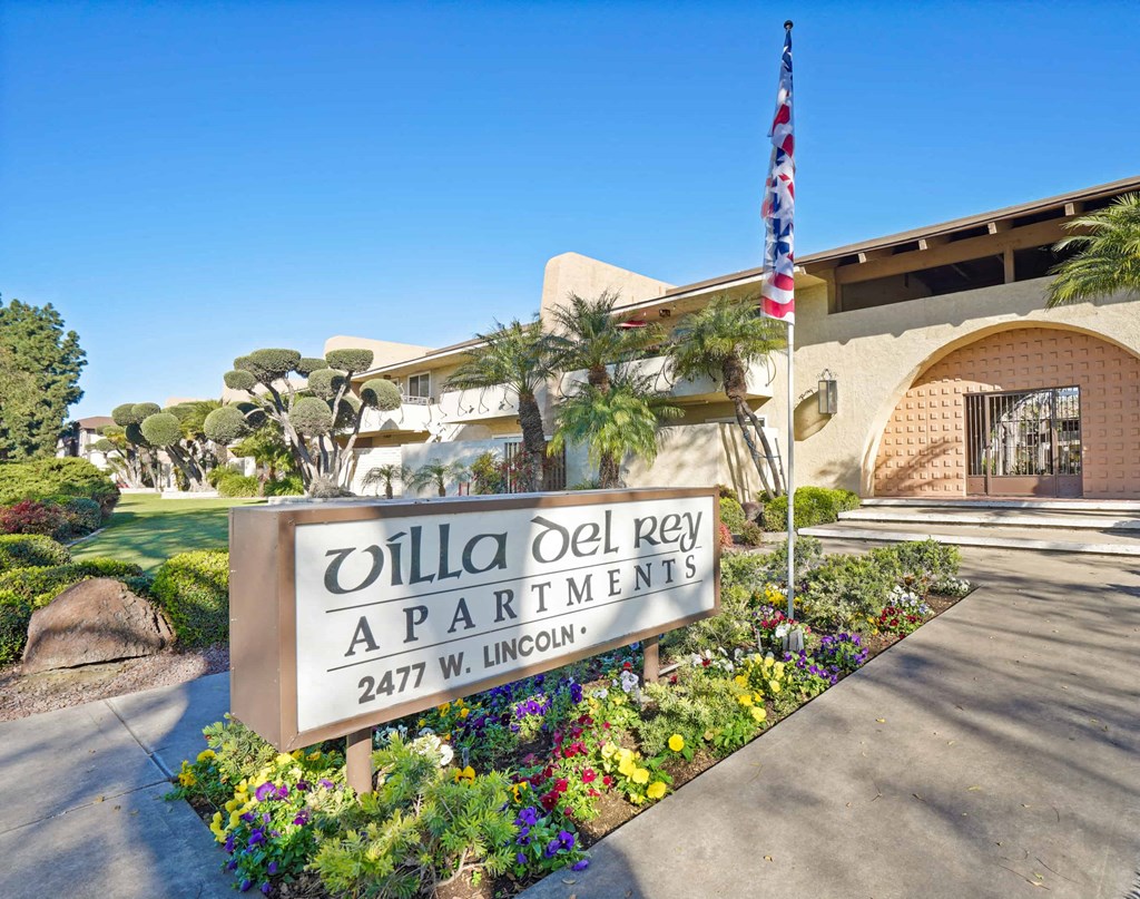 A sign for Villa Del Rey Apartments is in front of a building.