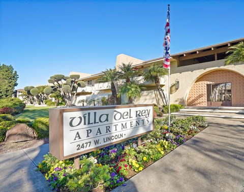 A sign for Villa Del Rey Apartments is in front of a building.