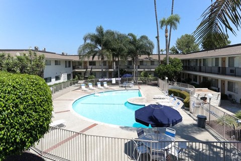 A pool area with a blue umbrella and chairs.