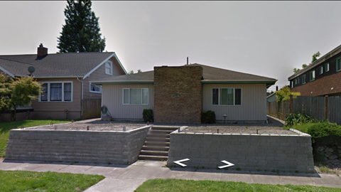 A house with a grey roof and a brown brick chimney.