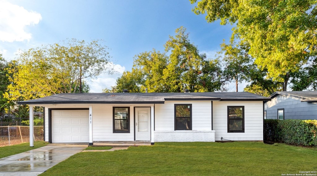 the front of a white house with a lawn and trees