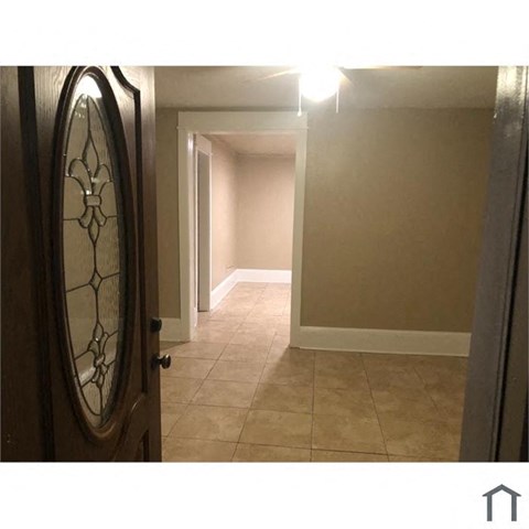 an empty hallway with a door with a mirror