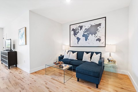 A living room with a blue couch and a world map on the wall.