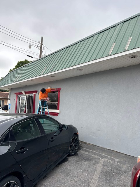 a man on a ladder painting the window of a building