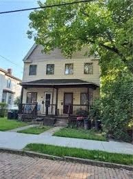 a yellow house with a porch and a sidewalk