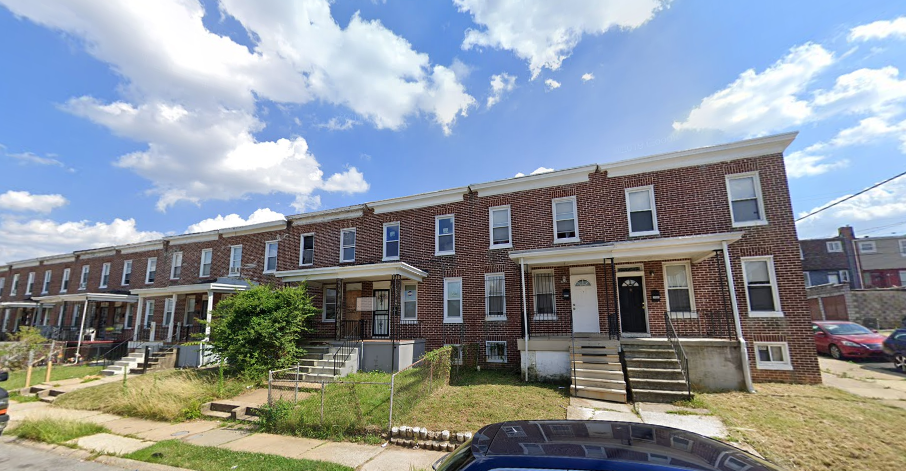 an old brick apartment building with stairs and grass in front of it
