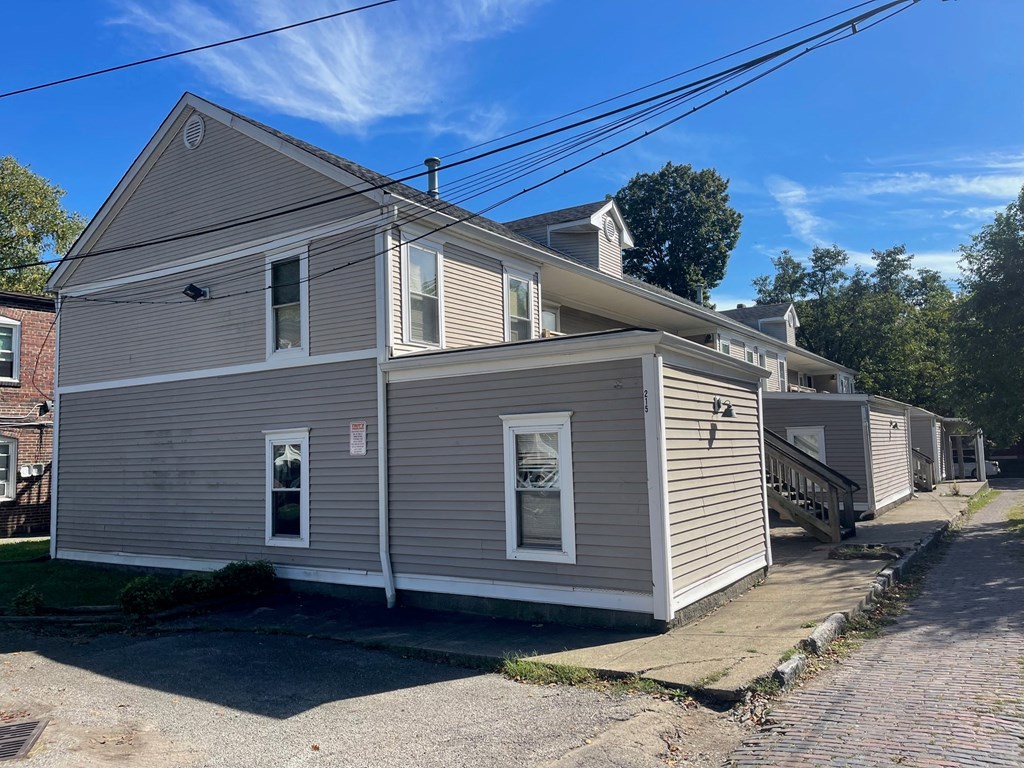 a white house with gray siding on the side of a street