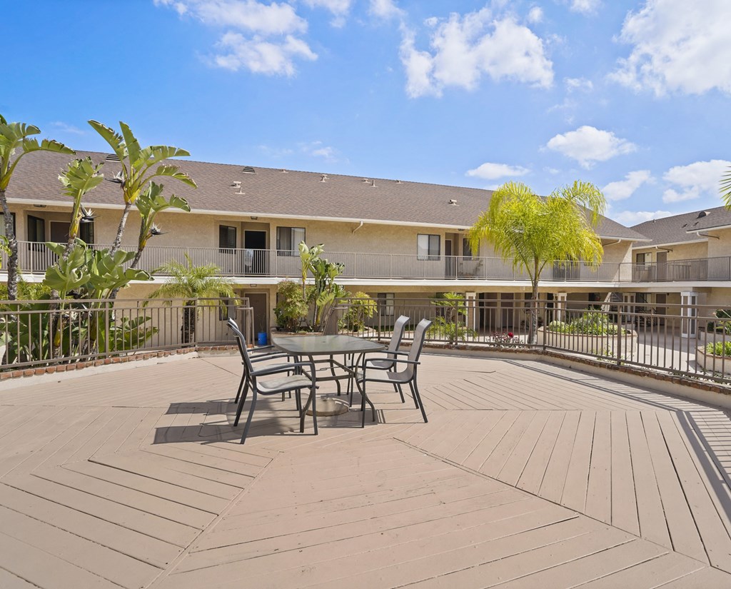 A patio with a table and chairs is surrounded by apartment buildings.