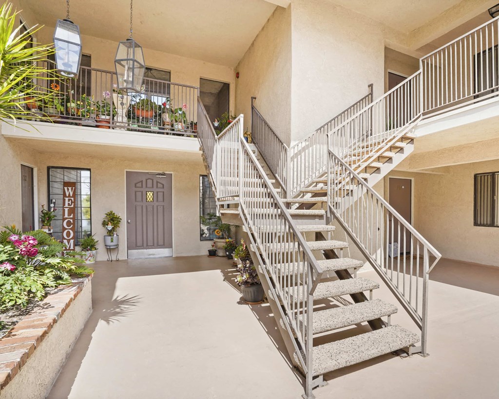 A staircase with metal railings leads to a second floor balcony.