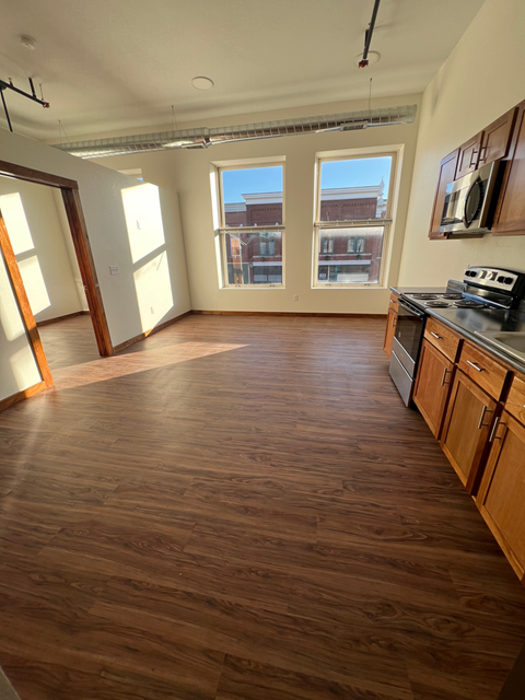 A room with wooden floors and a window overlooking a cityscape.
