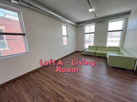 A living room with a green couch and wooden floors.