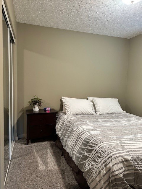 A bedroom with a bed, nightstand, and a plant.