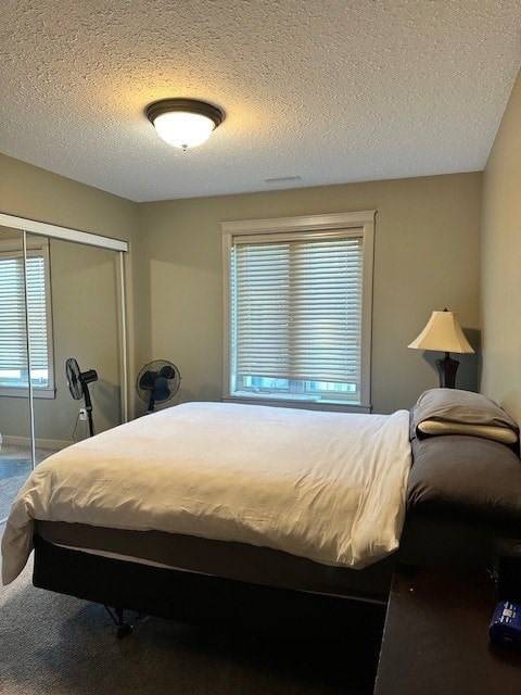 A bedroom with a bed, a fan, a window with blinds, and a lamp.