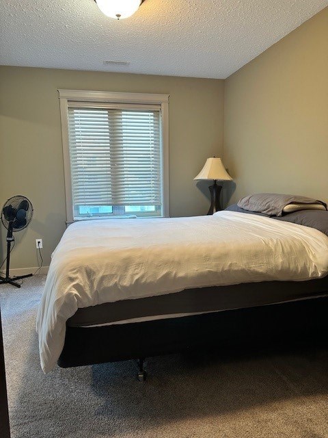 A bedroom with a bed, a fan, and a lamp.