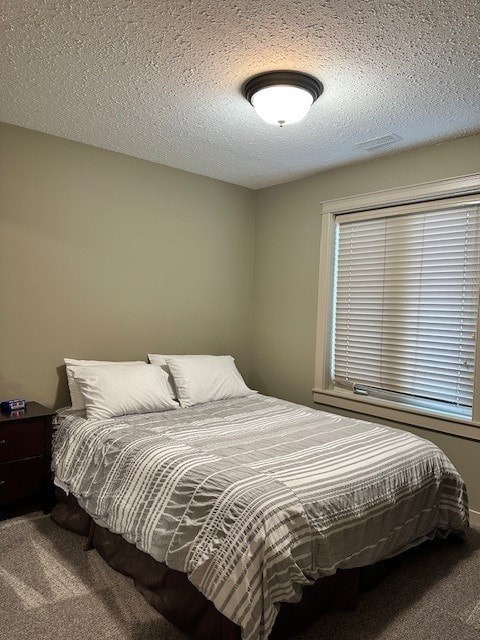 A bedroom with a bed, nightstand, and window with blinds.