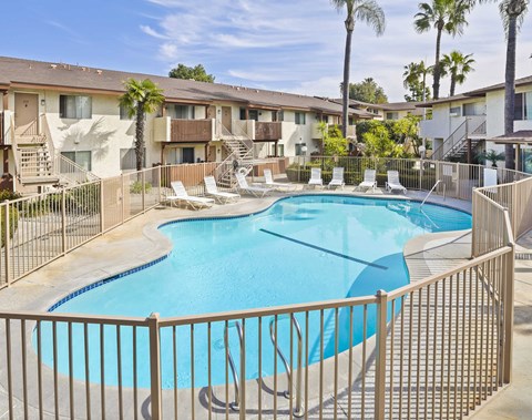 A pool surrounded by a fence and chairs.