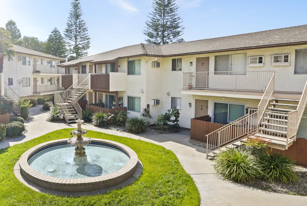A courtyard with a fountain and apartment buildings.