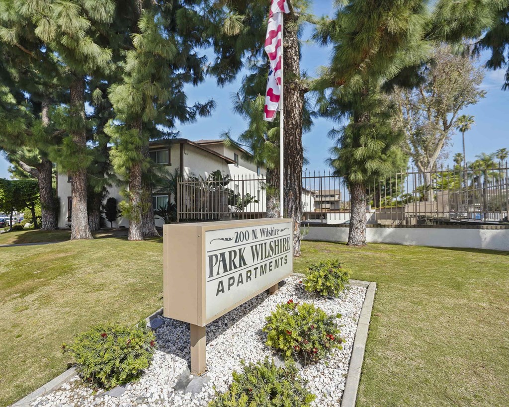 A sign for Park Wilshire Apartments stands in front of a house.