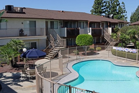 A pool surrounded by a metal fence and a building in the background.