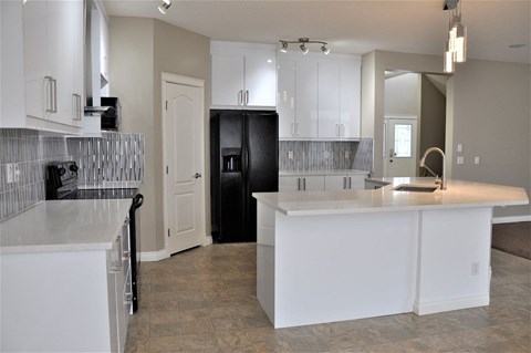 A kitchen with white cabinets and a black refrigerator.