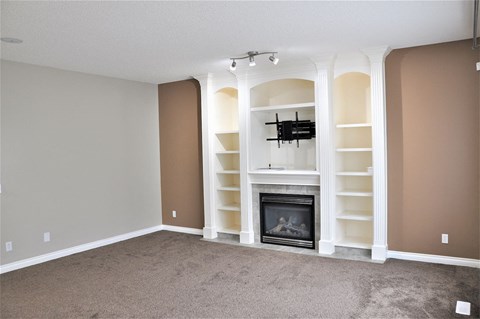 A living room with a fireplace and a TV mounted above it.
