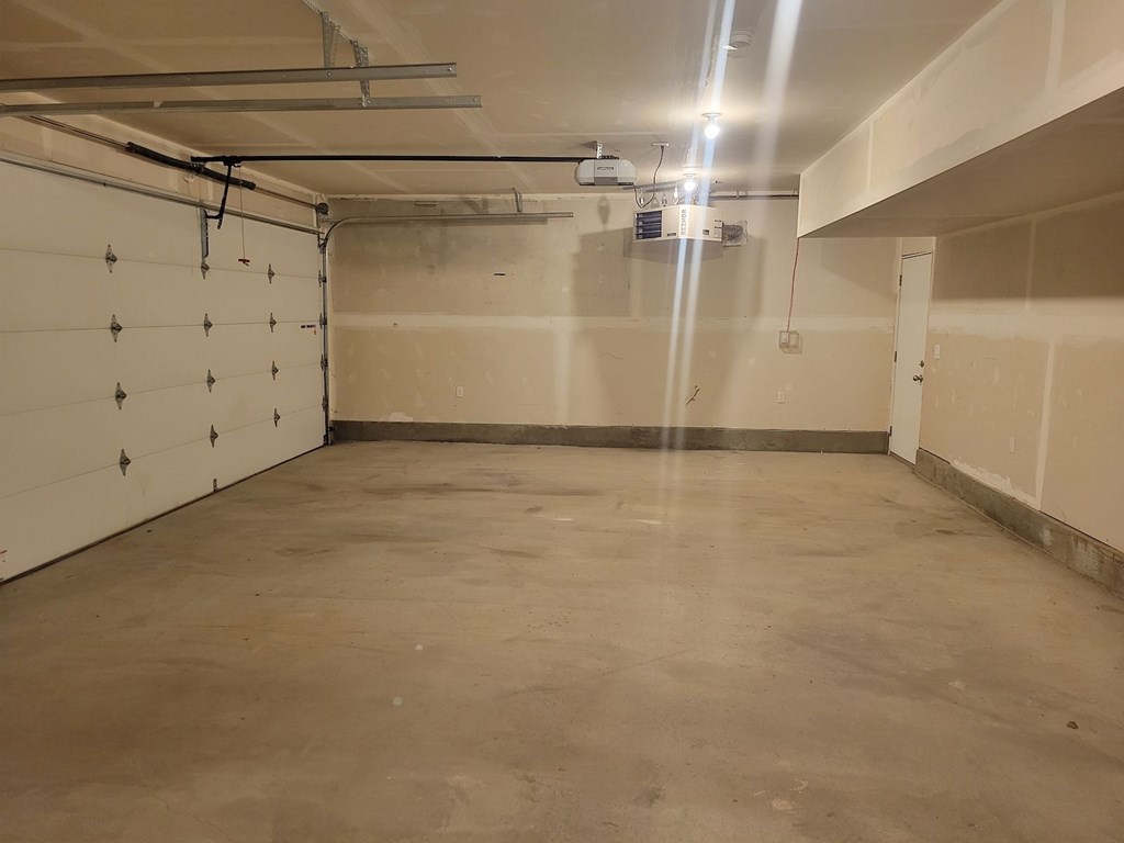 A spacious, empty room with a concrete floor and walls, and a row of metal hooks on the left wall.