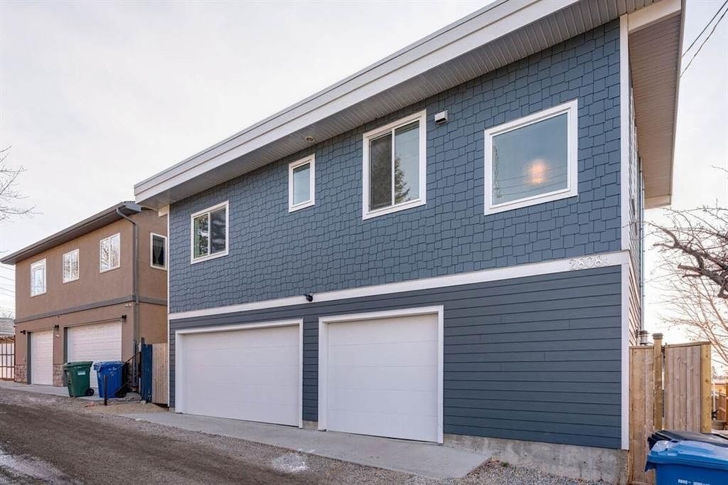 A two-story house with a blue exterior and white garage doors.