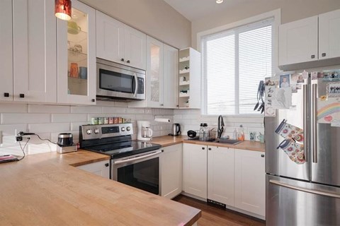 A kitchen with white cabinets and a wooden countertop.