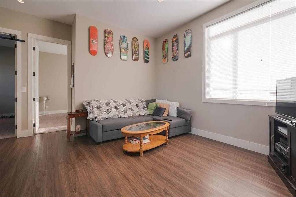 A living room with a grey couch, a coffee table, and a wall with skateboards on it.