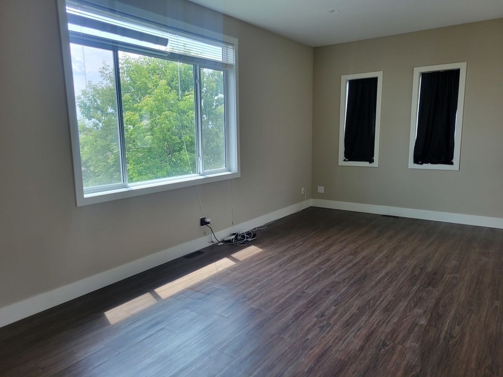 A room with a large window and wooden flooring.