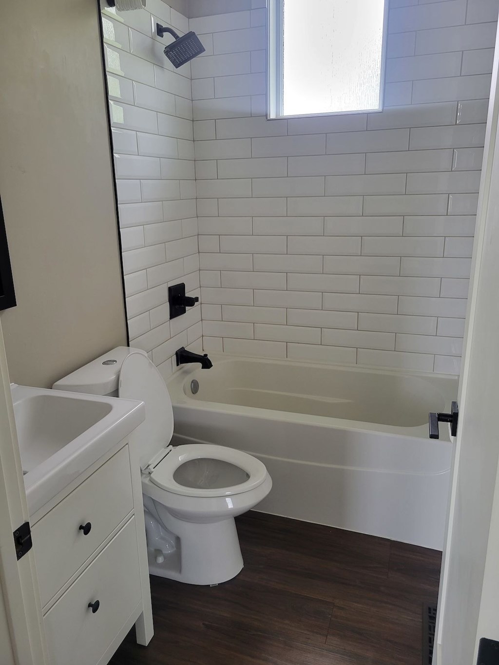 A white toilet in a bathroom with a white tiled wall.