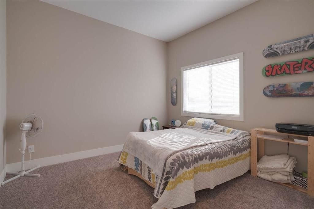 A bedroom with a bed, a window, and a skateboard on the wall.