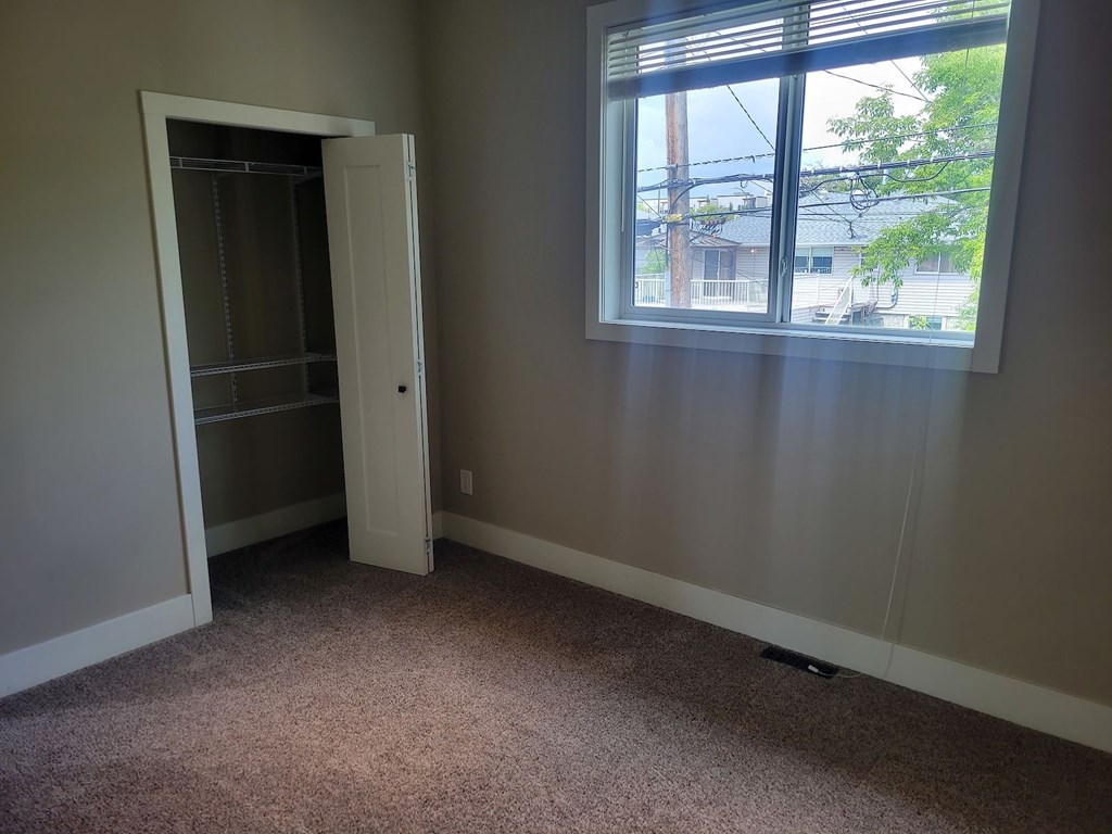 A room with a carpet floor, a window, and a door.
