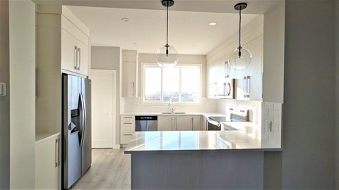 A modern kitchen with a refrigerator on the left and a countertop with a sink.