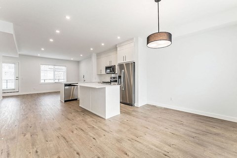 an open kitchen and living room with a island and a stainless steel refrigerator